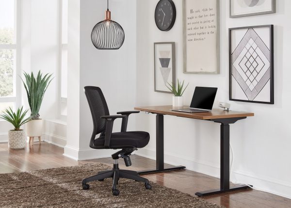 A desk and chair in front of a wall with a laptop on it.